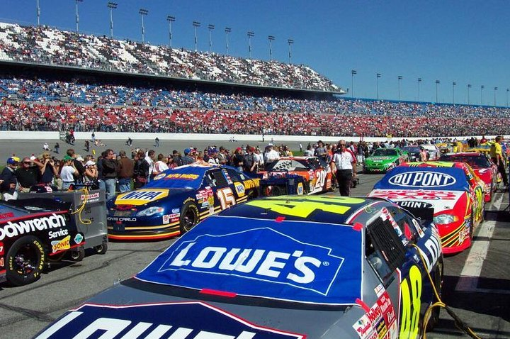 Feel the energy of NASCAR as cars line the Daytona International Speedway surrounded by passionate fans ready to celebrate The Great American Race in a historic setting.